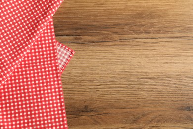 Photo of Red checkered tablecloth on wooden background, top view. Space for text