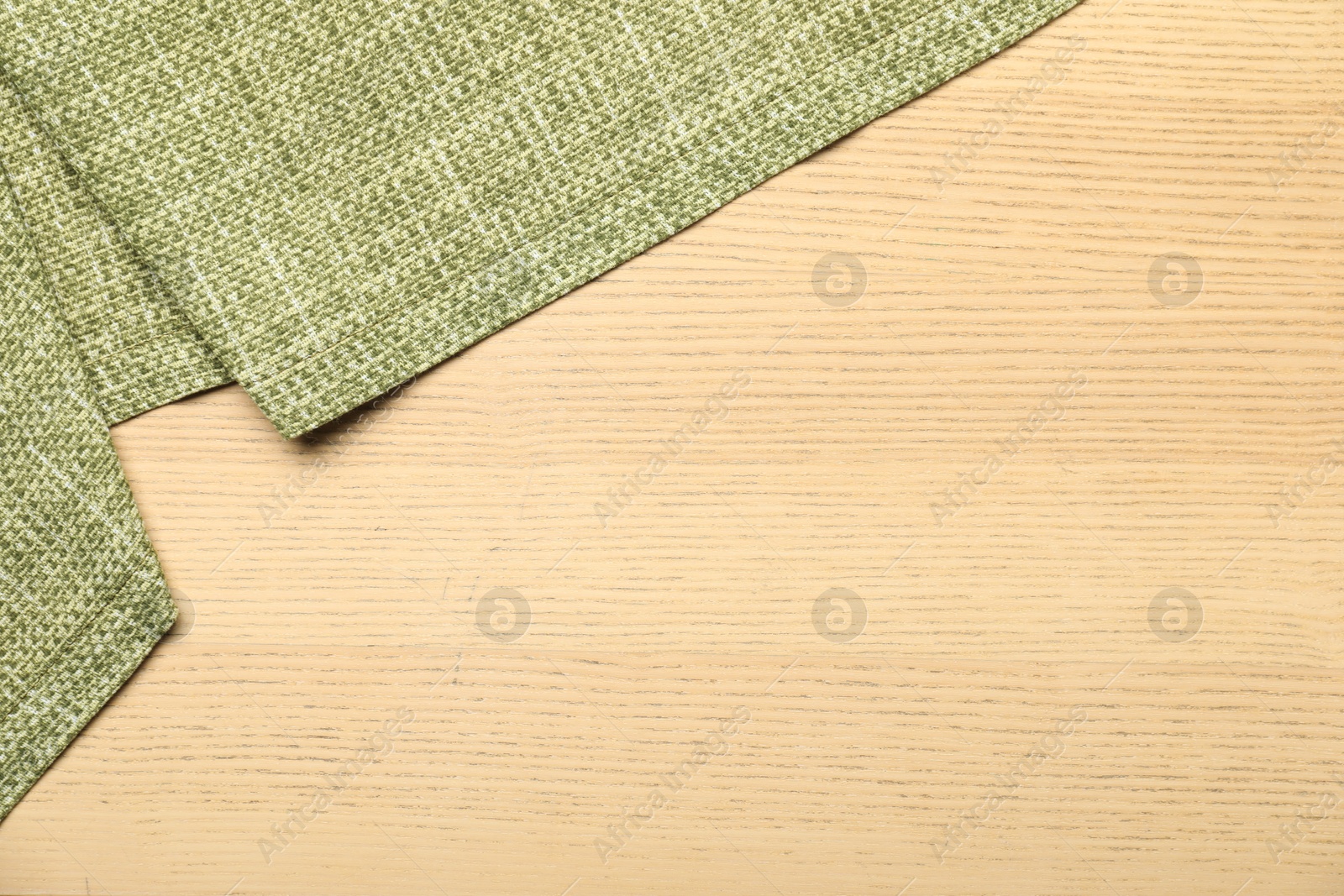 Photo of Green tablecloth on wooden background, top view. Space for text