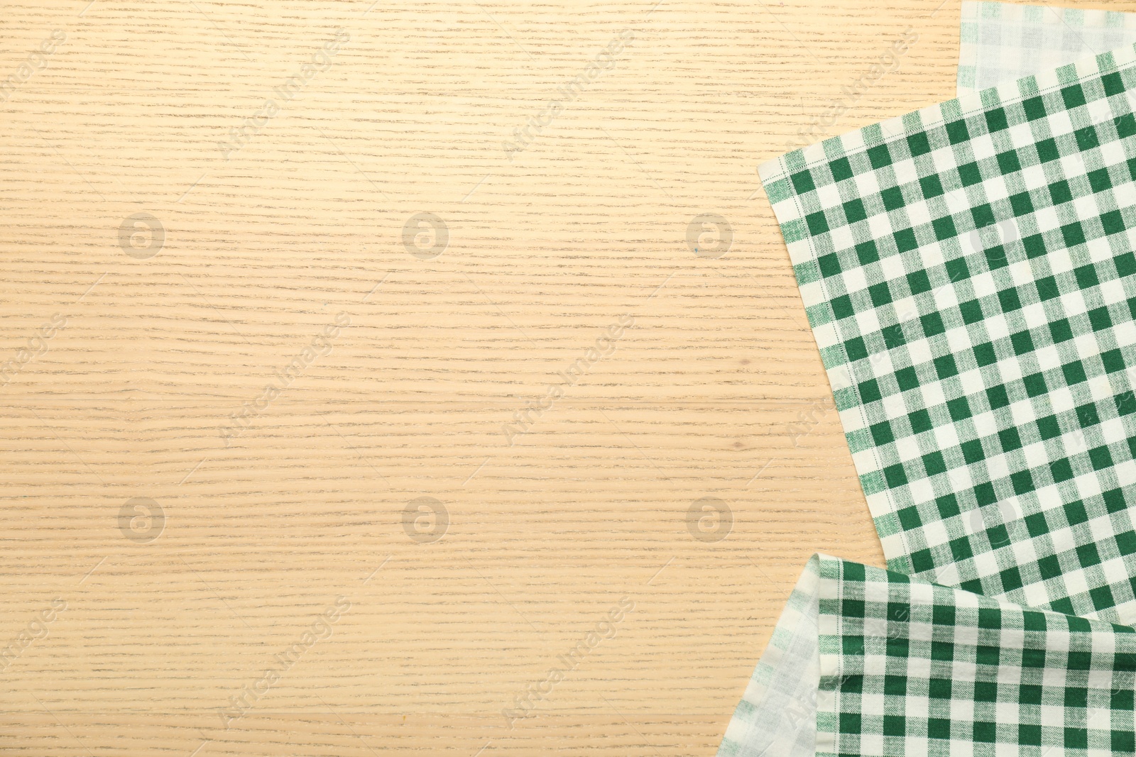 Photo of Green checkered tablecloth on wooden background, top view. Space for text