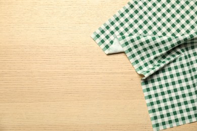 Photo of Green checkered tablecloth on wooden background, top view. Space for text