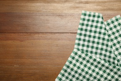 Photo of Green checkered tablecloth on wooden background, top view. Space for text