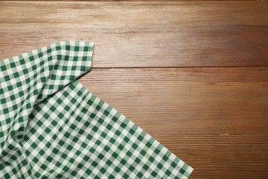 Photo of Green checkered tablecloth on wooden background, top view. Space for text