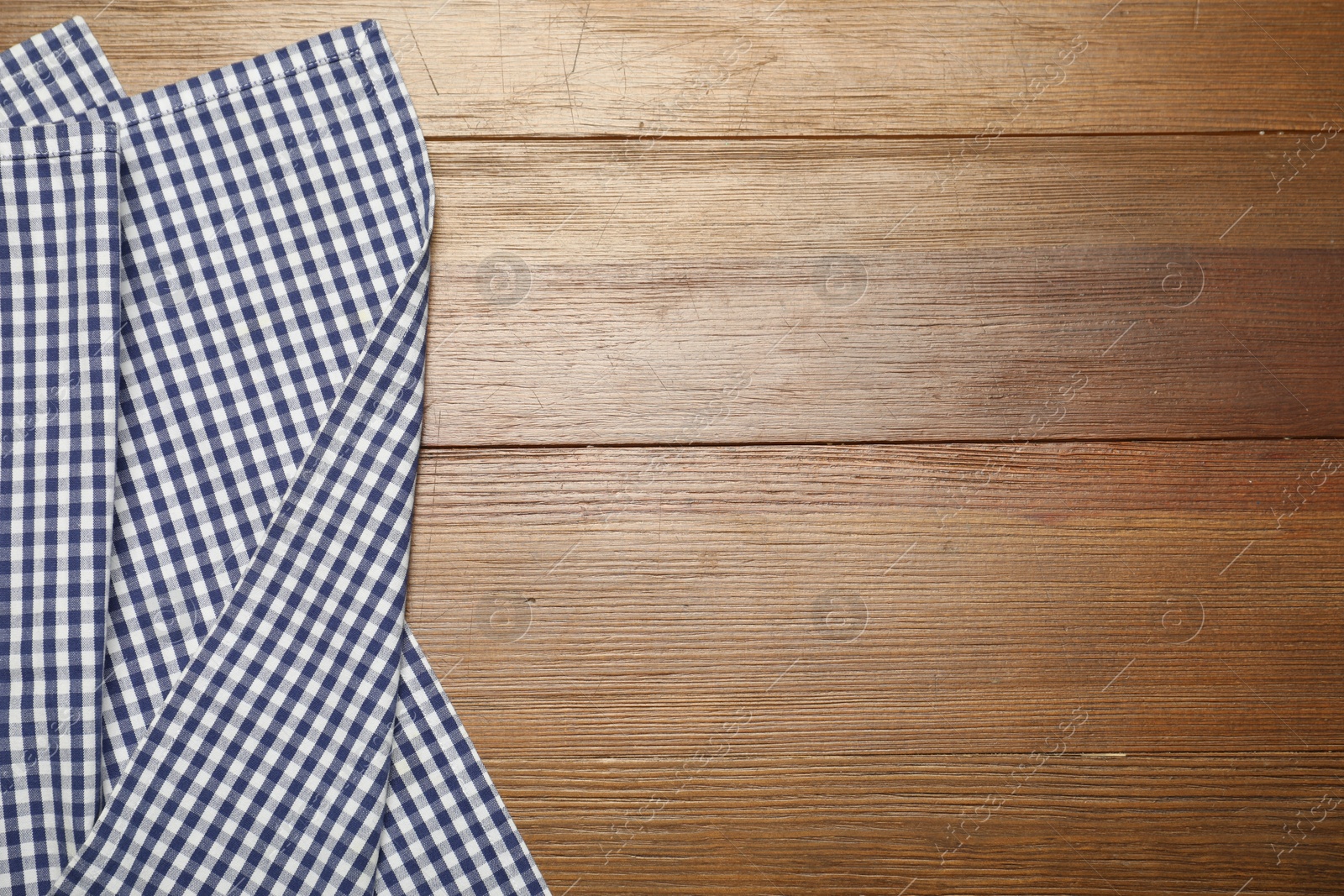 Photo of Blue checkered tablecloth on wooden background, top view. Space for text