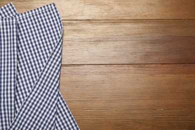 Photo of Blue checkered tablecloth on wooden background, top view. Space for text