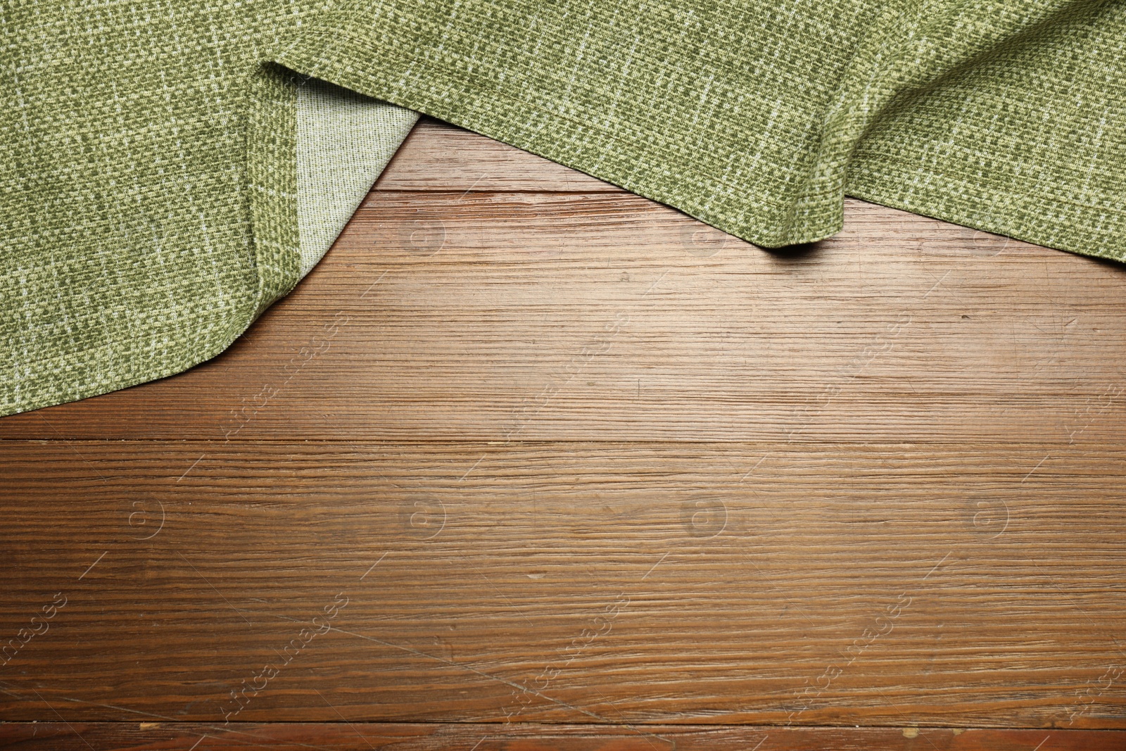 Photo of Green tablecloth on wooden background, top view. Space for text