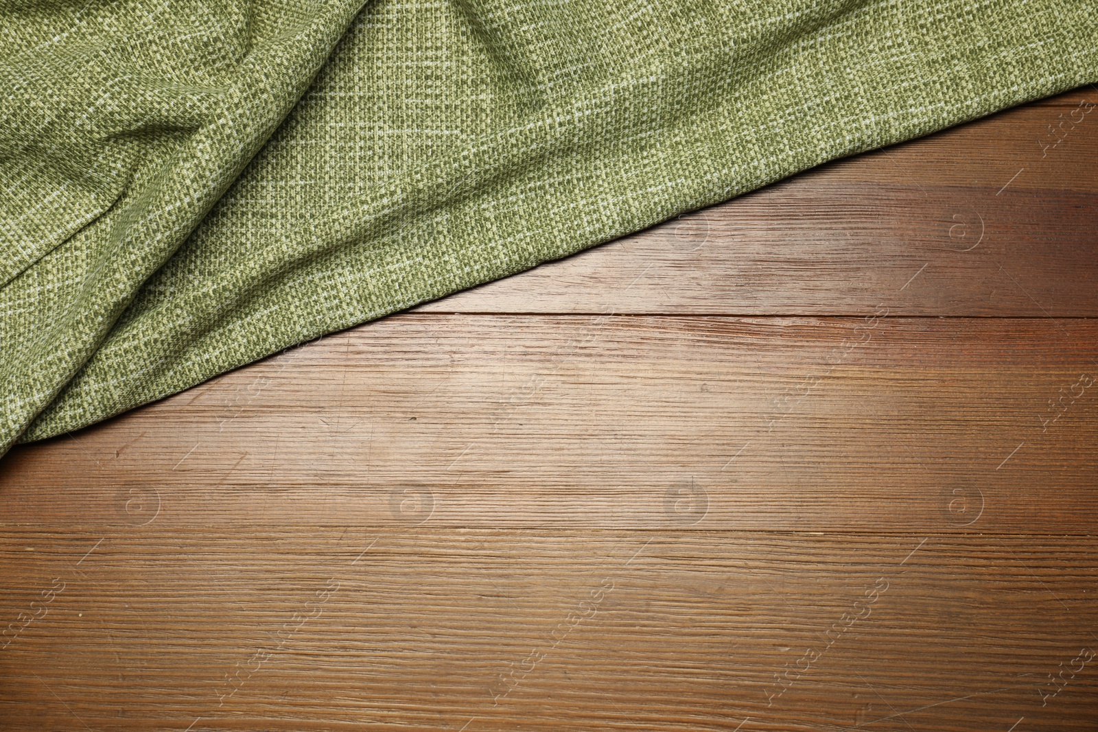 Photo of Green tablecloth on wooden background, top view. Space for text