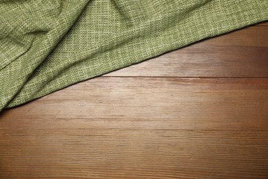 Photo of Green tablecloth on wooden background, top view. Space for text