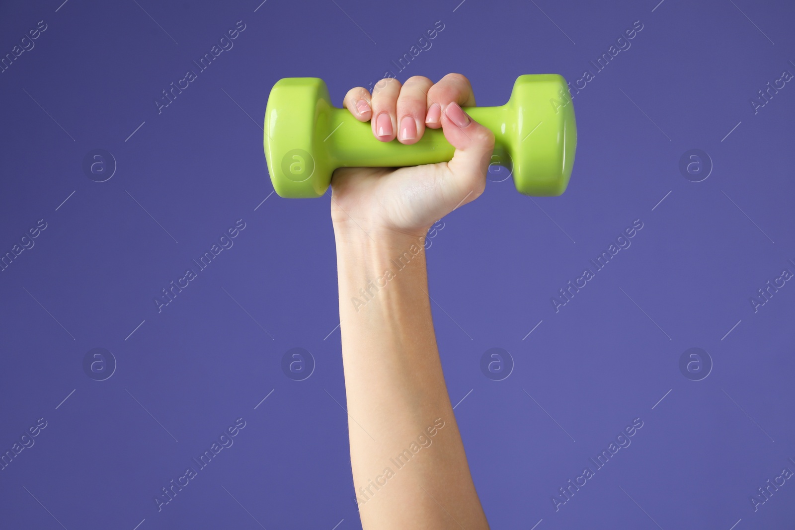 Photo of Woman exercising with dumbbell on purple background, closeup