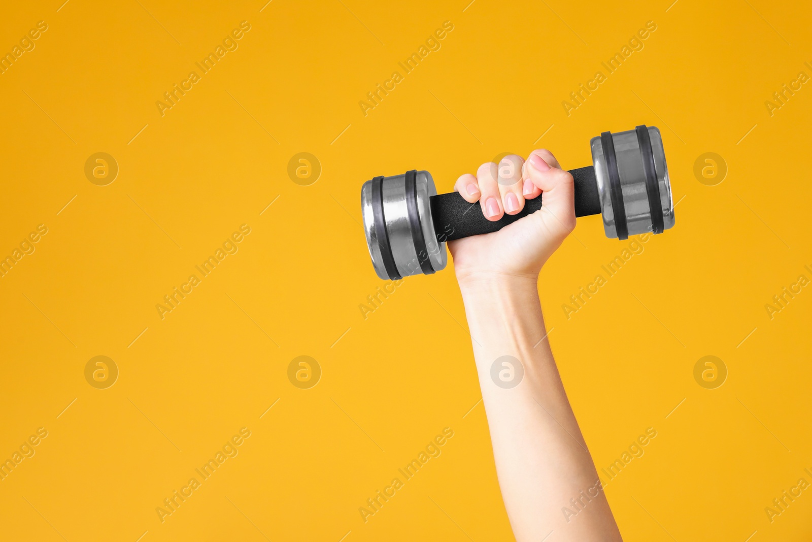 Photo of Woman exercising with dumbbell on orange background, closeup. Space for text