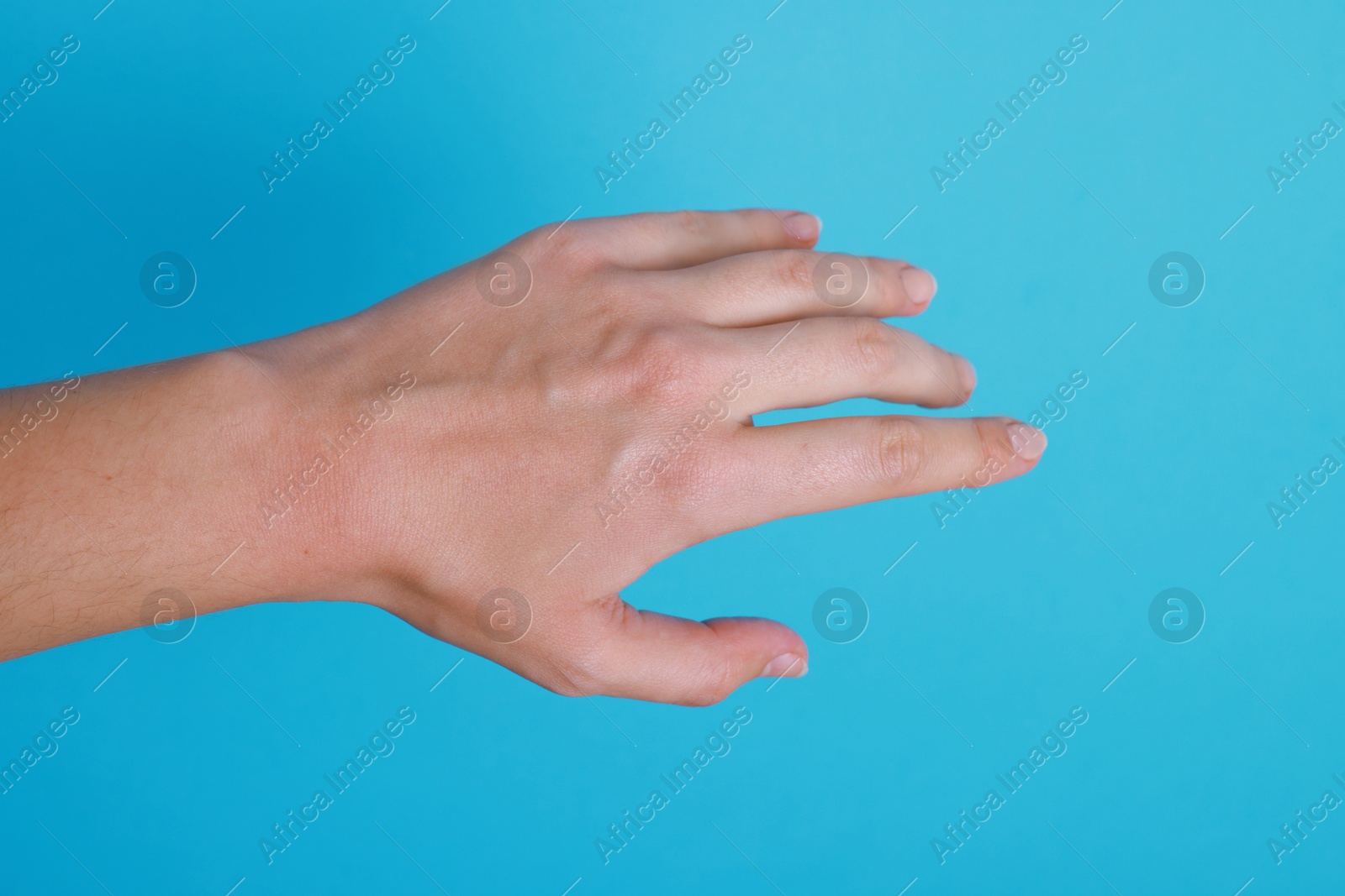 Photo of Woman with visible hand veins on light blue background, closeup