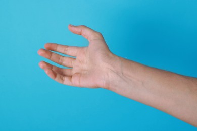 Photo of Woman with visible hand veins on light blue background, closeup