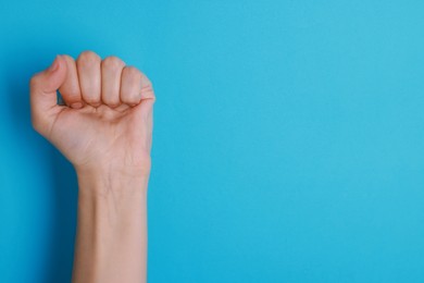 Photo of Woman with visible hand veins on light blue background, closeup. Space for text