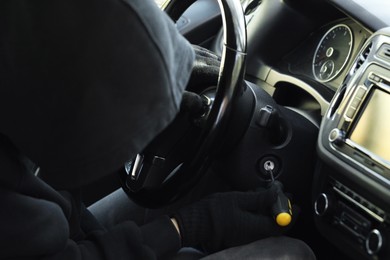 Photo of Thief trying to start ignition switch with screwdriver, closeup. Car hijacking