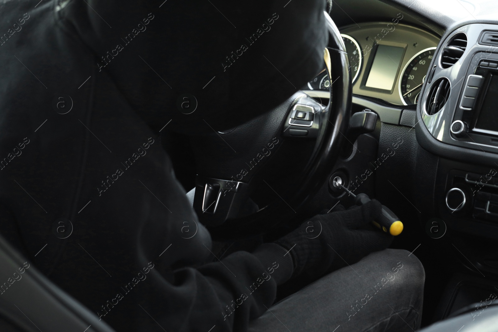 Photo of Thief trying to start ignition switch with screwdriver, closeup. Car hijacking