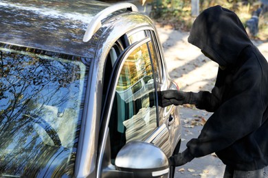 Photo of Thief breaking into modern auto. Car hijacking