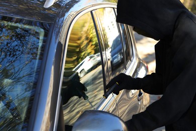 Photo of Thief with screwdriver breaking into auto, closeup. Car hijacking