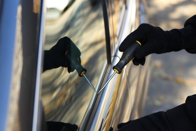 Photo of Thief with screwdriver breaking into auto, closeup. Car hijacking