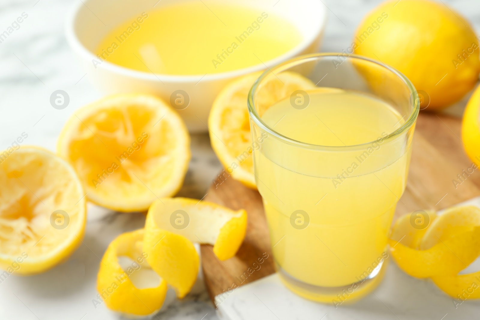 Photo of Glass of fresh lemon juice and squeezed fruits on table, closeup