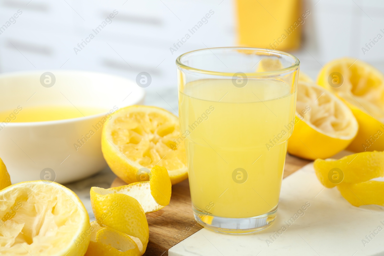 Photo of Glass of fresh lemon juice and squeezed fruits on table, closeup