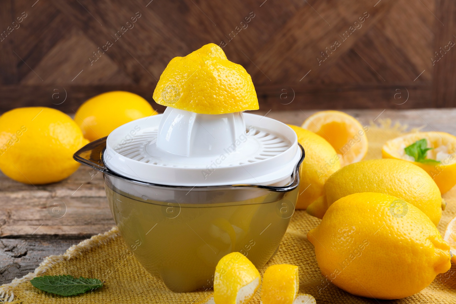 Photo of Juicer and fresh lemons on wooden table