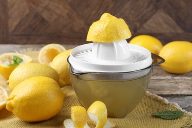 Photo of Juicer and fresh lemons on wooden table