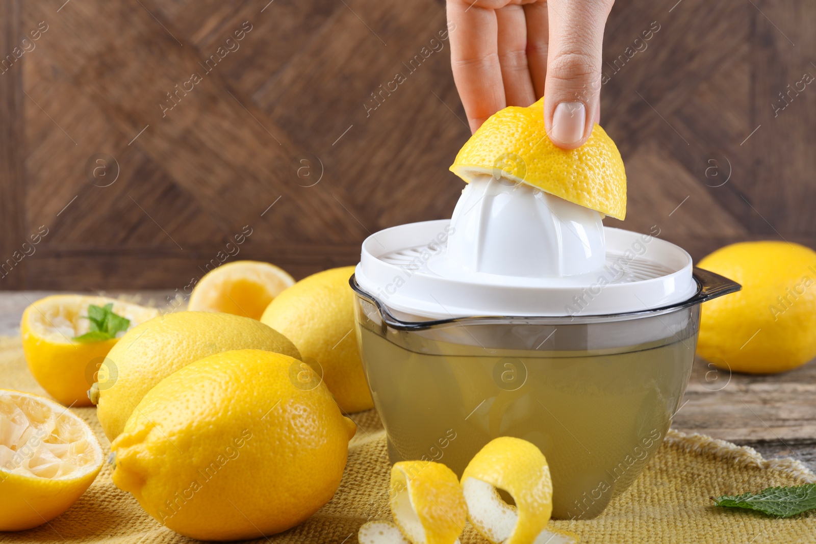 Photo of Woman with lemon using juicer at wooden table, closeup