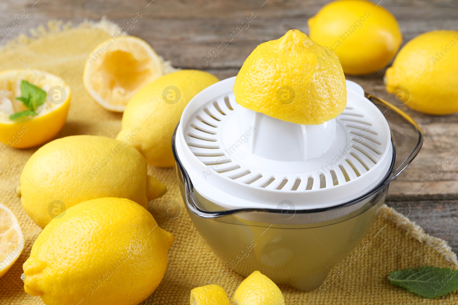 Photo of Juicer and fresh lemons on wooden table, closeup