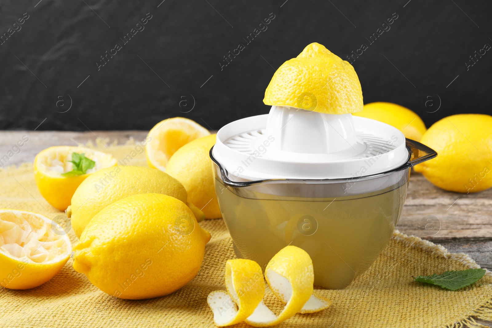 Photo of Juicer and fresh lemons on wooden table