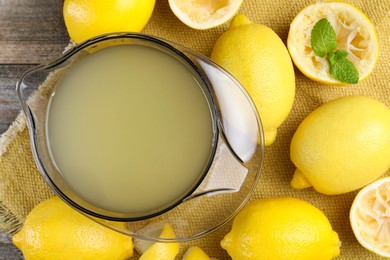 Photo of Fresh lemon juice and fruits on wooden table, flat lay