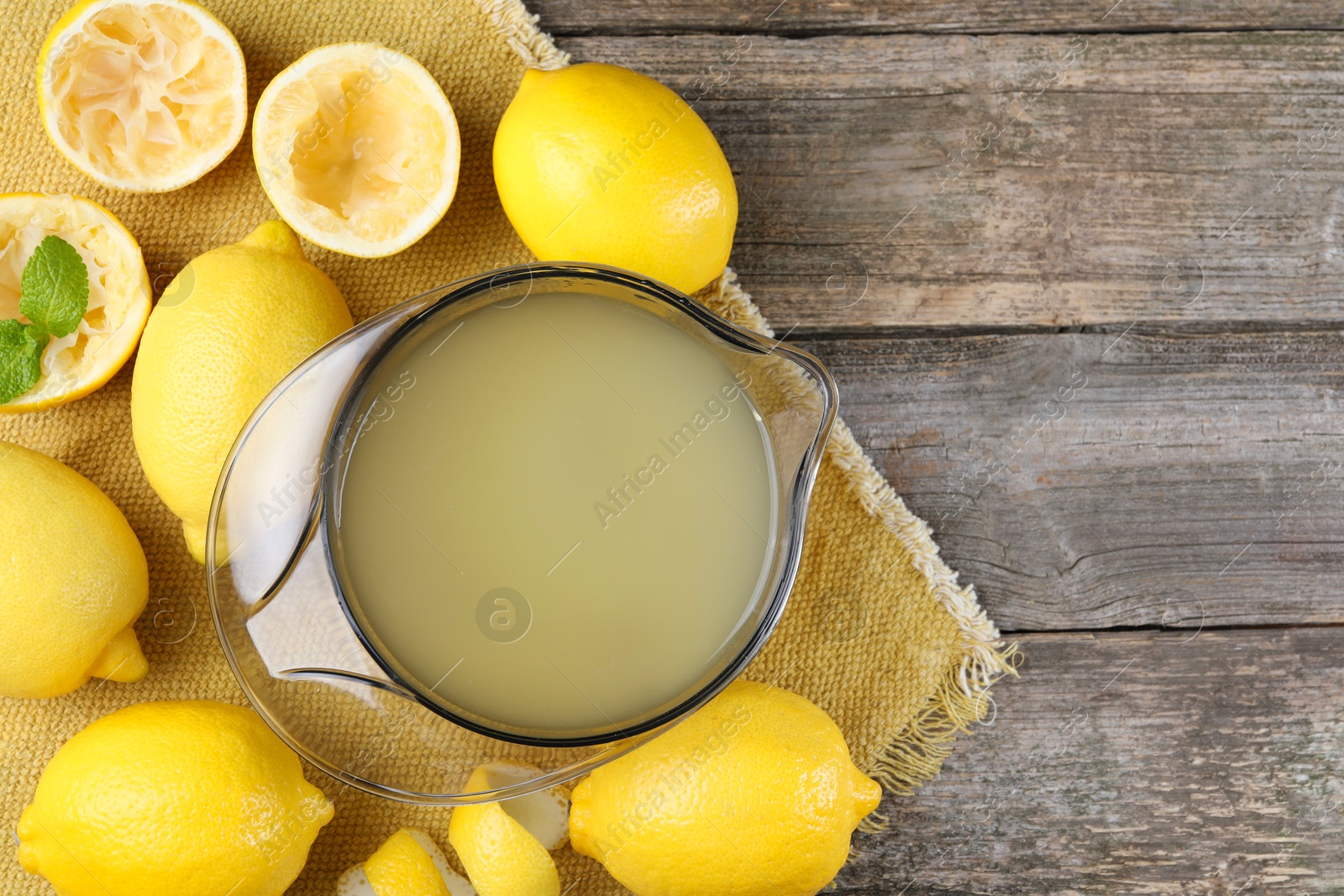 Photo of Fresh lemon juice and fruits on wooden table, flat lay. Space for text