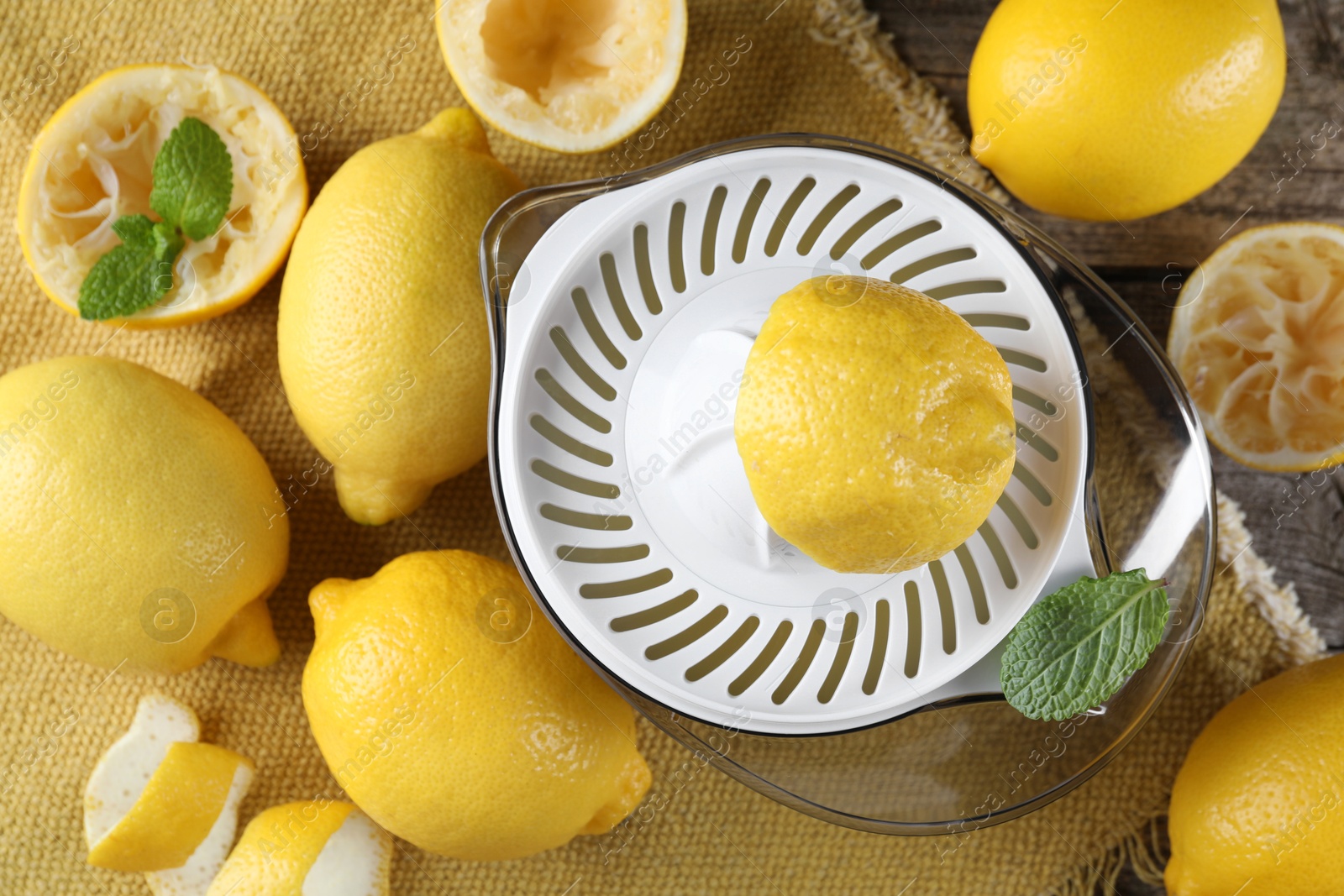 Photo of Juicer and fresh lemons on wooden table, top view