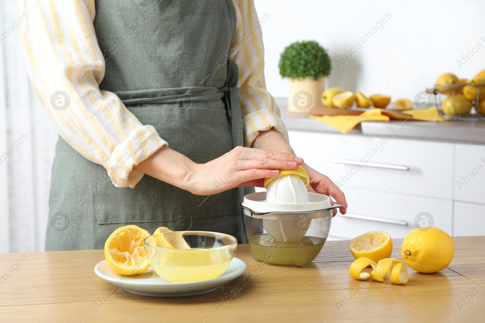 Photo of Woman with lemon using juicer at wooden table, closeup