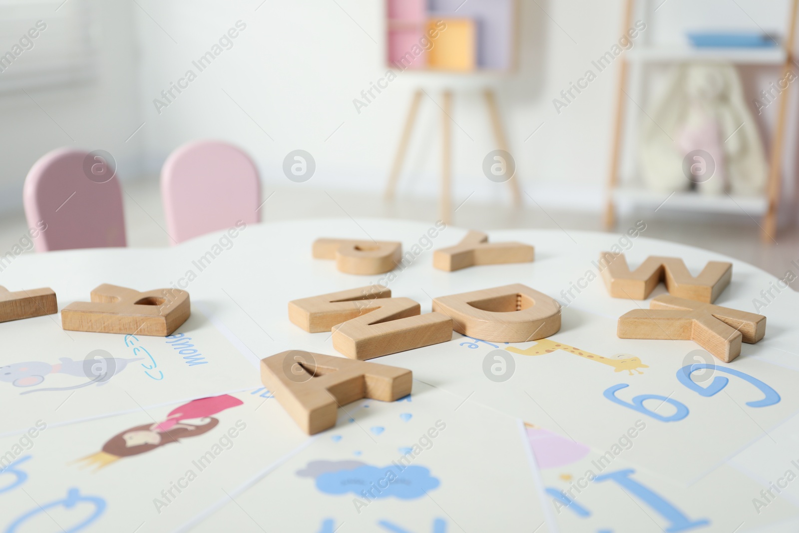 Photo of Learning alphabet. Different wooden letters and pictures on white table indoors