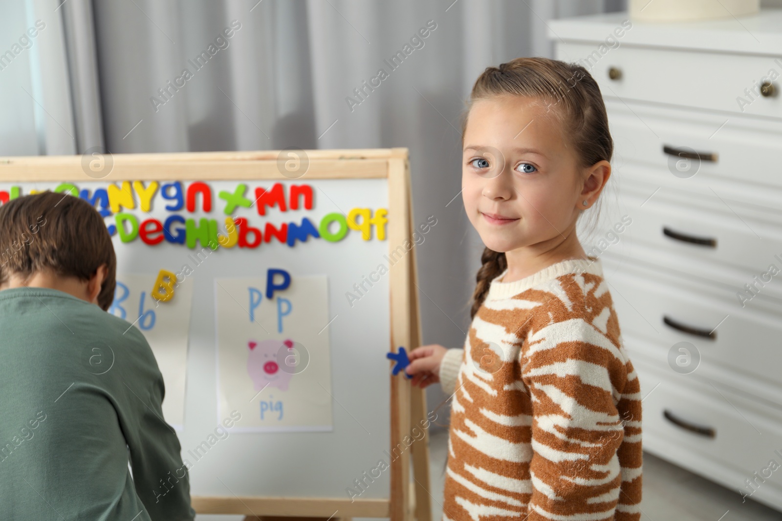 Photo of Little kids learning alphabet with magnetic letters indoors