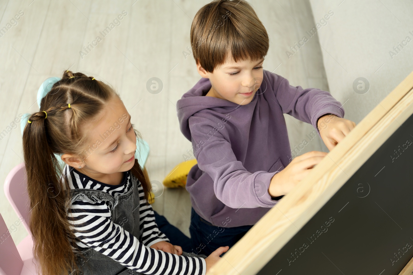 Photo of Little kids learning alphabet near board indoors