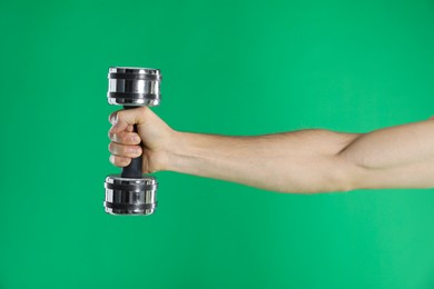 Photo of Man exercising with dumbbell on green background, closeup