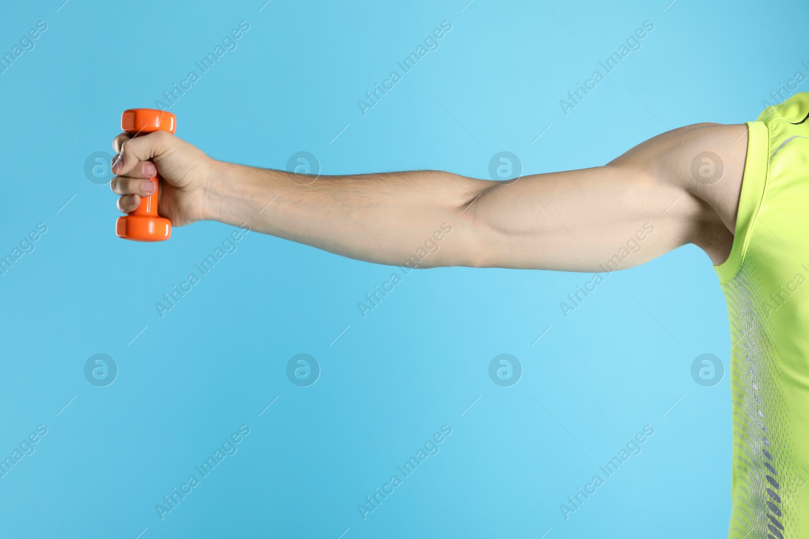 Photo of Man exercising with dumbbell on light blue background, closeup