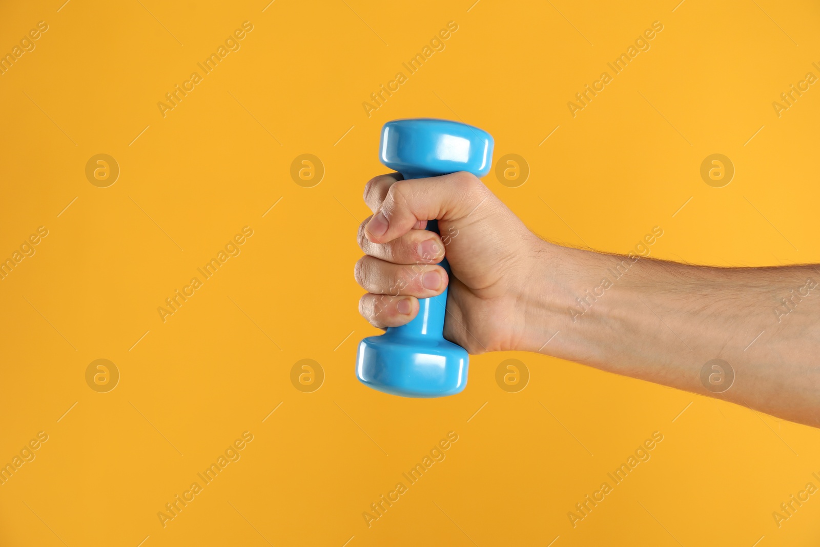 Photo of Man exercising with dumbbell on yellow background, closeup. Space for text