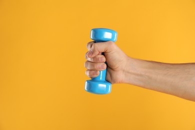 Photo of Man exercising with dumbbell on yellow background, closeup. Space for text