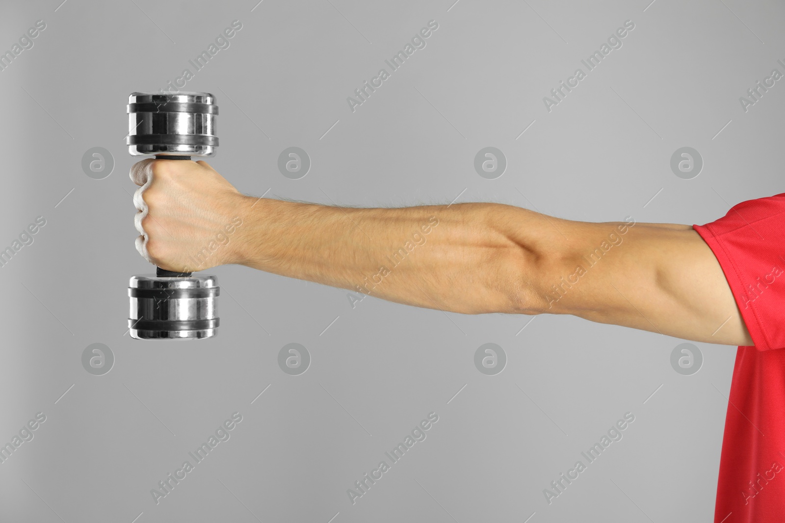 Photo of Man exercising with dumbbell on grey background, closeup