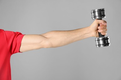 Photo of Man exercising with dumbbell on grey background, closeup