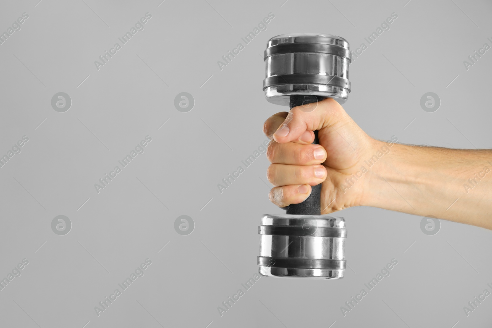 Photo of Man exercising with dumbbell on grey background, closeup. Space for text