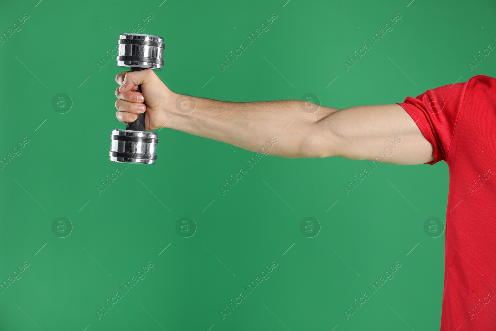 Photo of Man exercising with dumbbell on green background, closeup