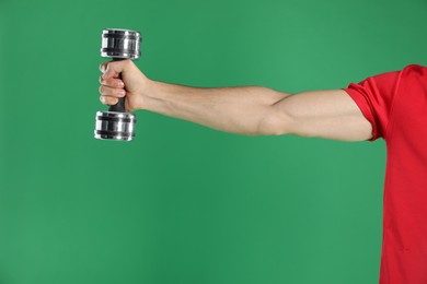 Photo of Man exercising with dumbbell on green background, closeup