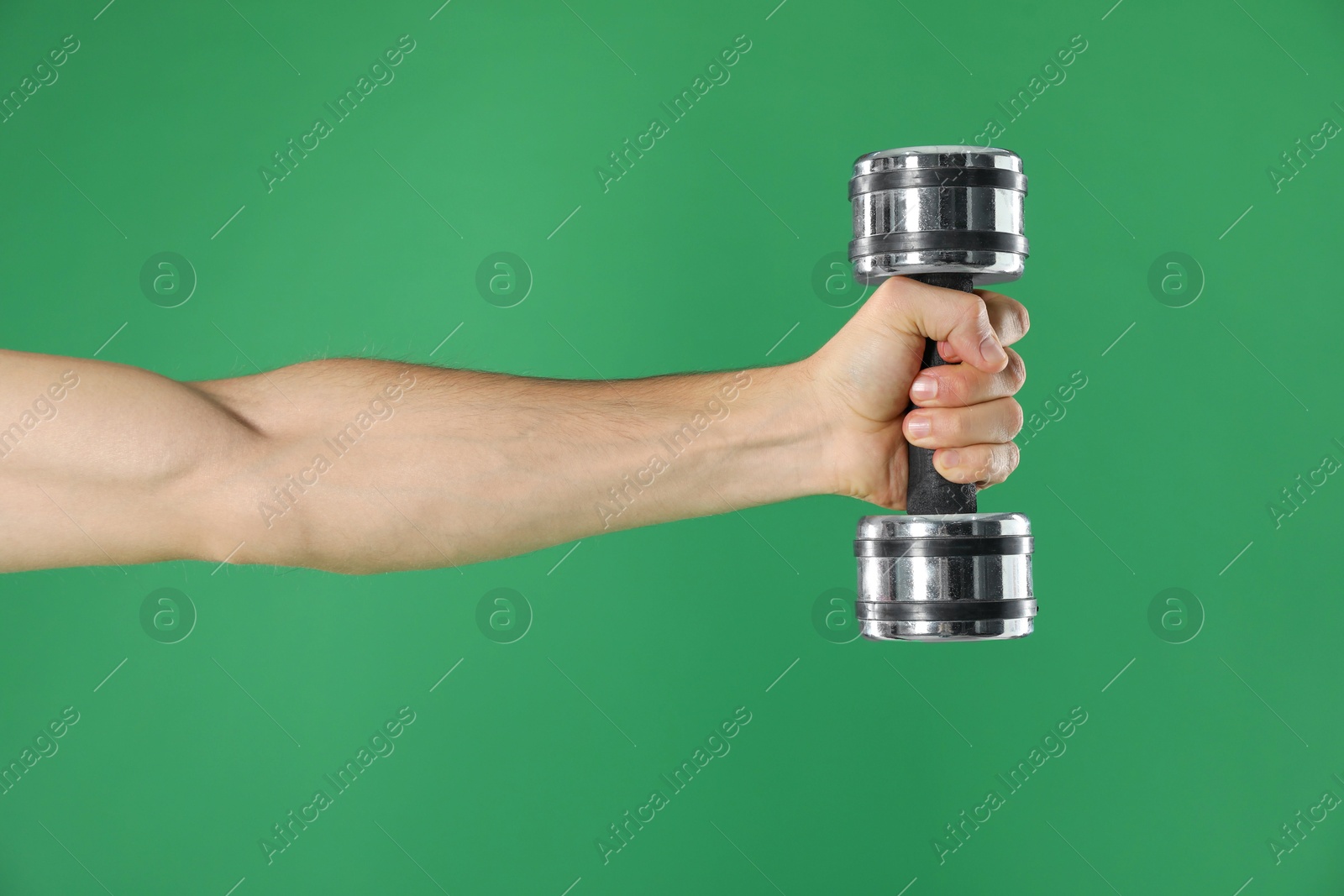 Photo of Man exercising with dumbbell on green background, closeup