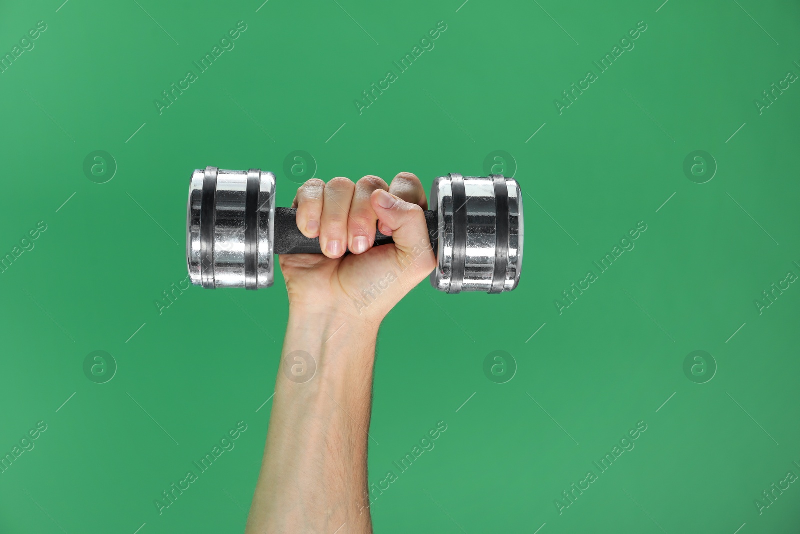 Photo of Man exercising with dumbbell on green background, closeup