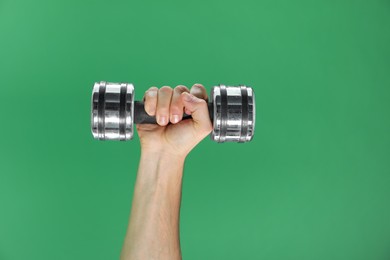 Photo of Man exercising with dumbbell on green background, closeup