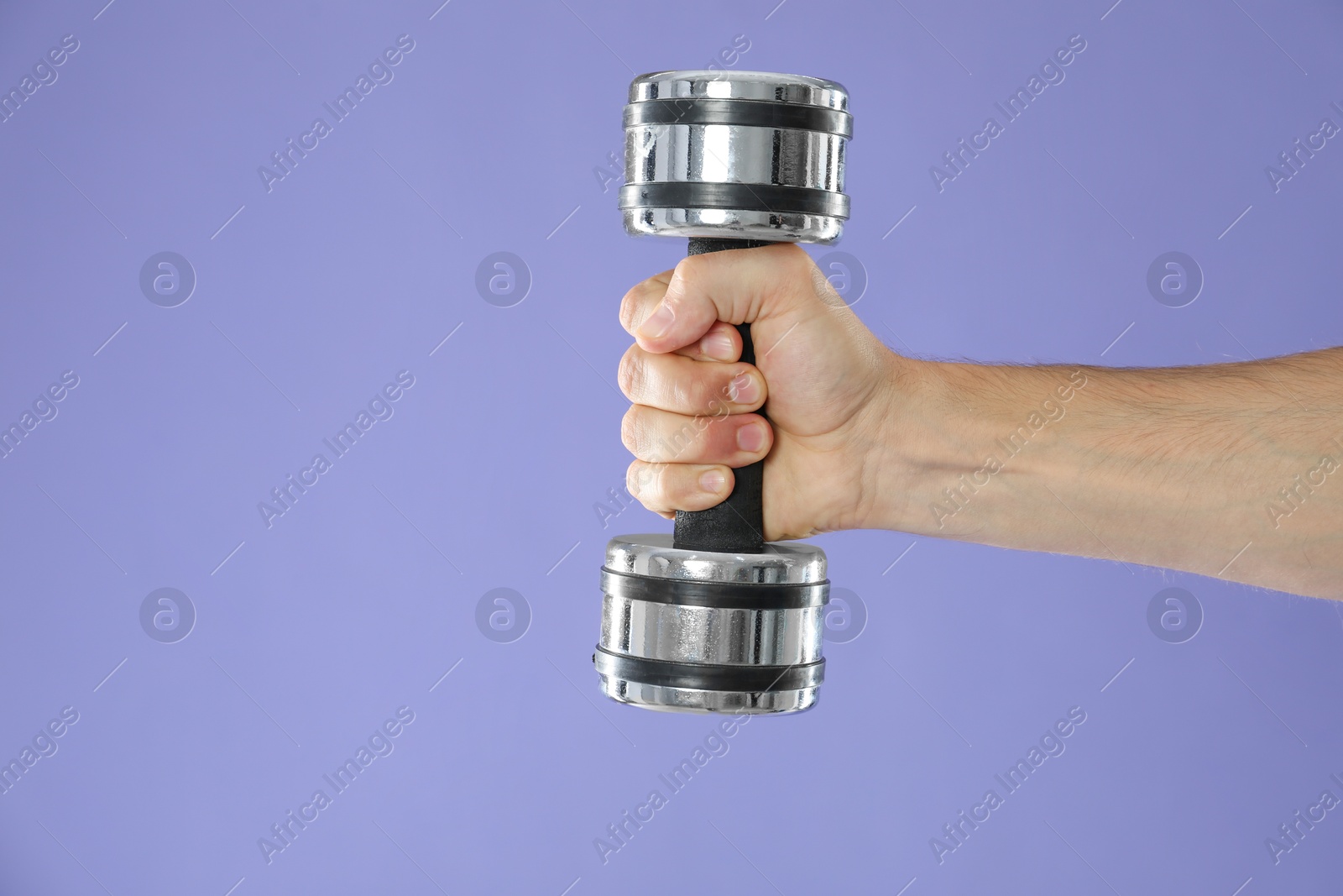 Photo of Man exercising with dumbbell on violet background, closeup. Space for text