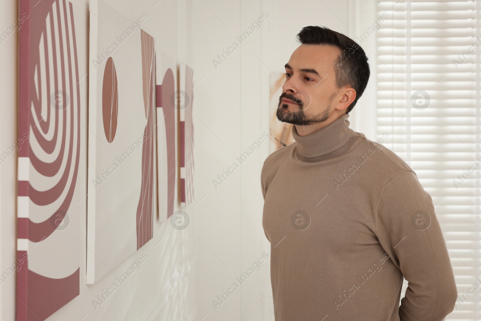 Photo of Man studying beautiful artwork in modern gallery