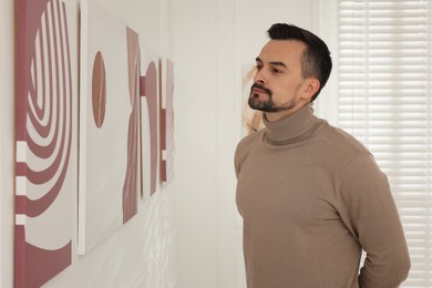 Photo of Man studying beautiful artwork in modern gallery